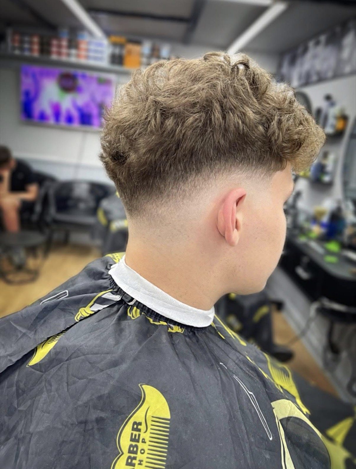 Curly hair left long on top with a tapered back and sides