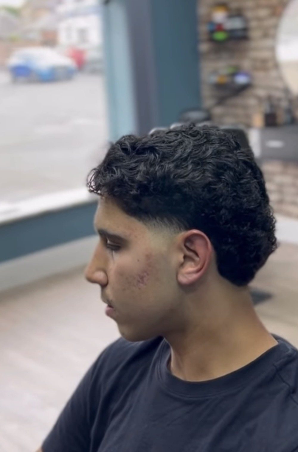 Curly hair taper cut in the window of Cygneture Barbers in Swanland